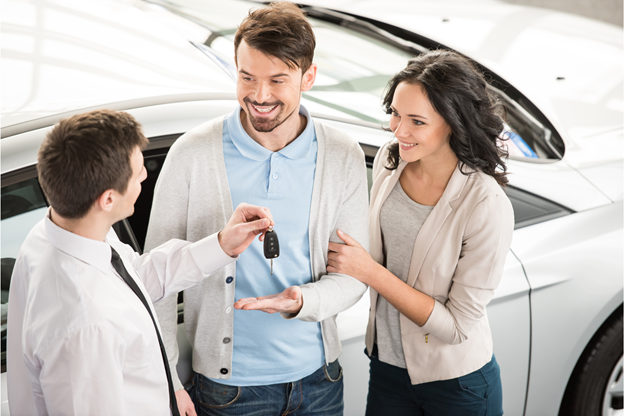 A picture of a couple who bought a new car from a car salesman